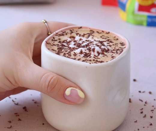 Taza de cerámica que contiene un moka. La bebida tiene una capa de espuma decorada con chocolate rayado