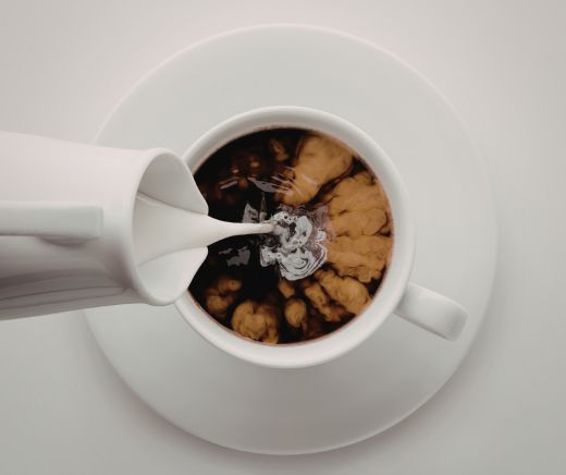 Taza blanca de con café un jarra espumadora color blanco rellenando de espuma de leche.