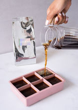 Cargar imagen en el visor de la galería, Jarra de vidrio transparente mientras vierte cafe en moldes rosas
